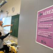Instituteur et élève masqués et affichette Aérez
